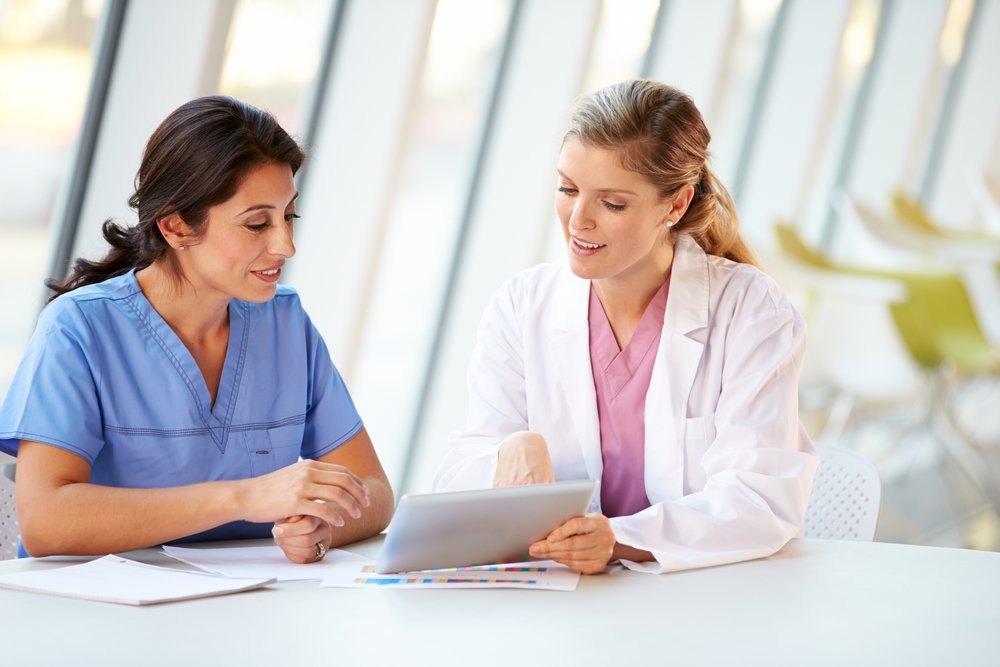 Female Doctor And Nurse Having Meeting In Hospital Canteen